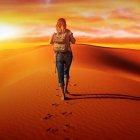 Person in wide-brimmed hat walking on sandy desert dune at sunset