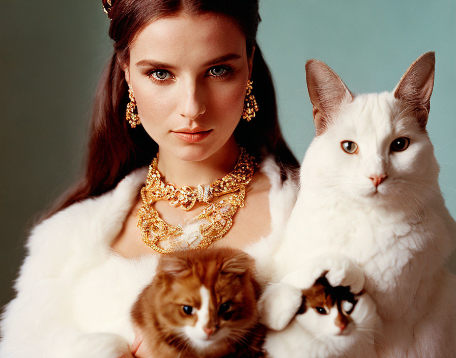 Dark-haired woman with jewelry posing with three cats on soft background