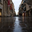 Moody urban street scene at dusk with neon signs reflected on wet roads