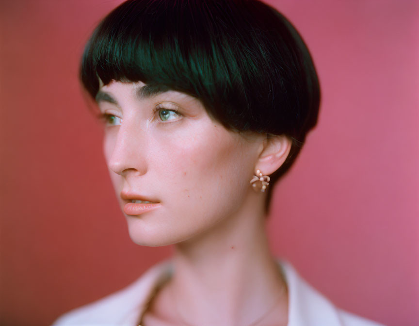 Woman with Short Black Bob Haircut in White Top Against Pink Background