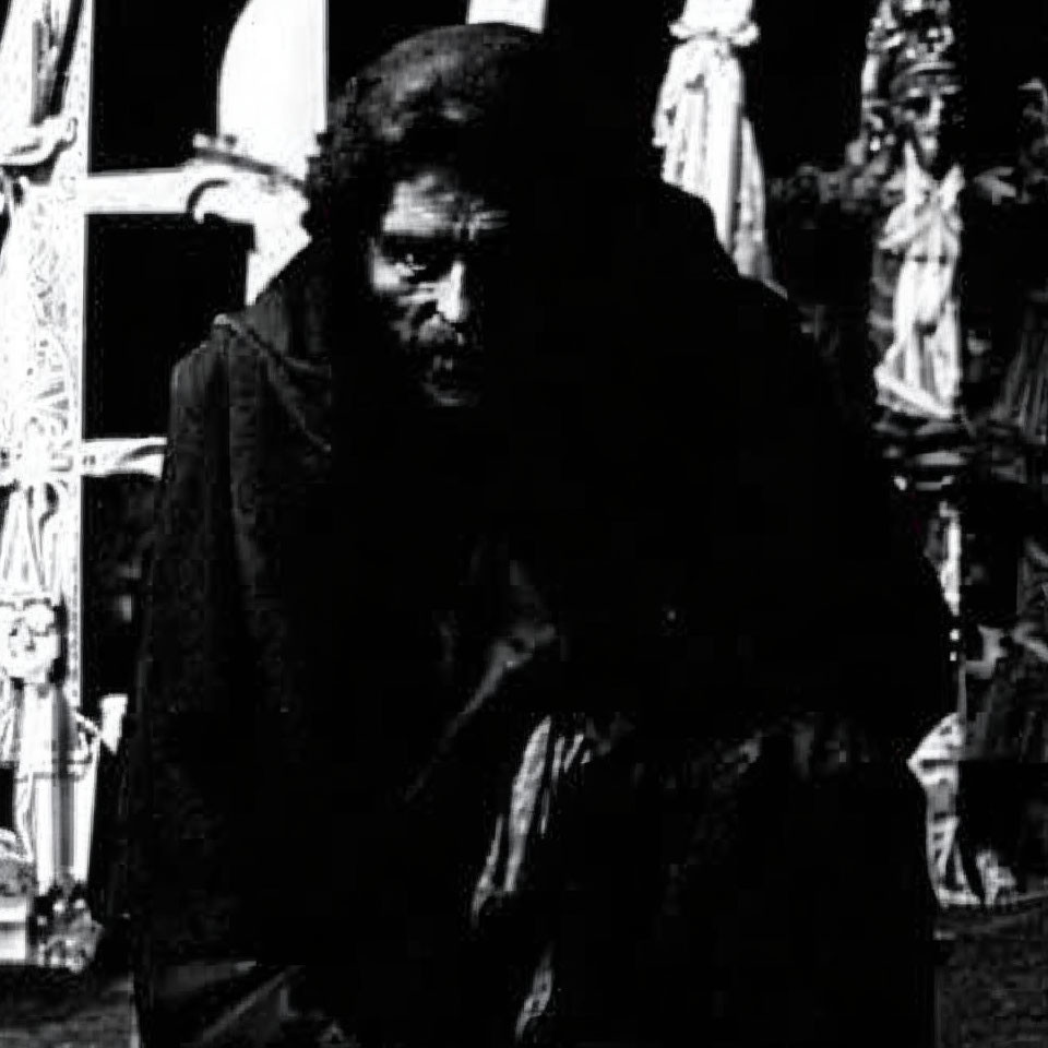 Pensive person in dark cloak, high-contrast black and white photo