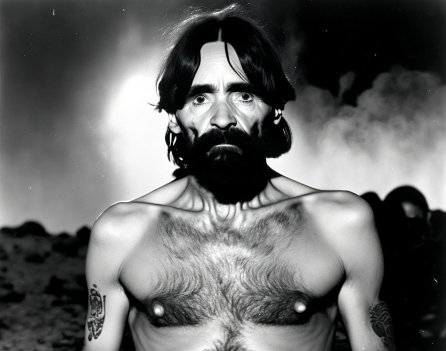 Monochrome portrait of bearded man with tattoos in smoke backdrop