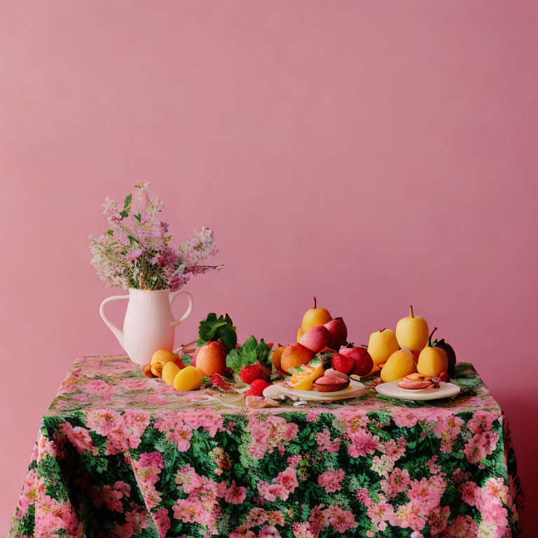 Floral tablecloth with fresh fruits and white jug of wildflowers on pink background