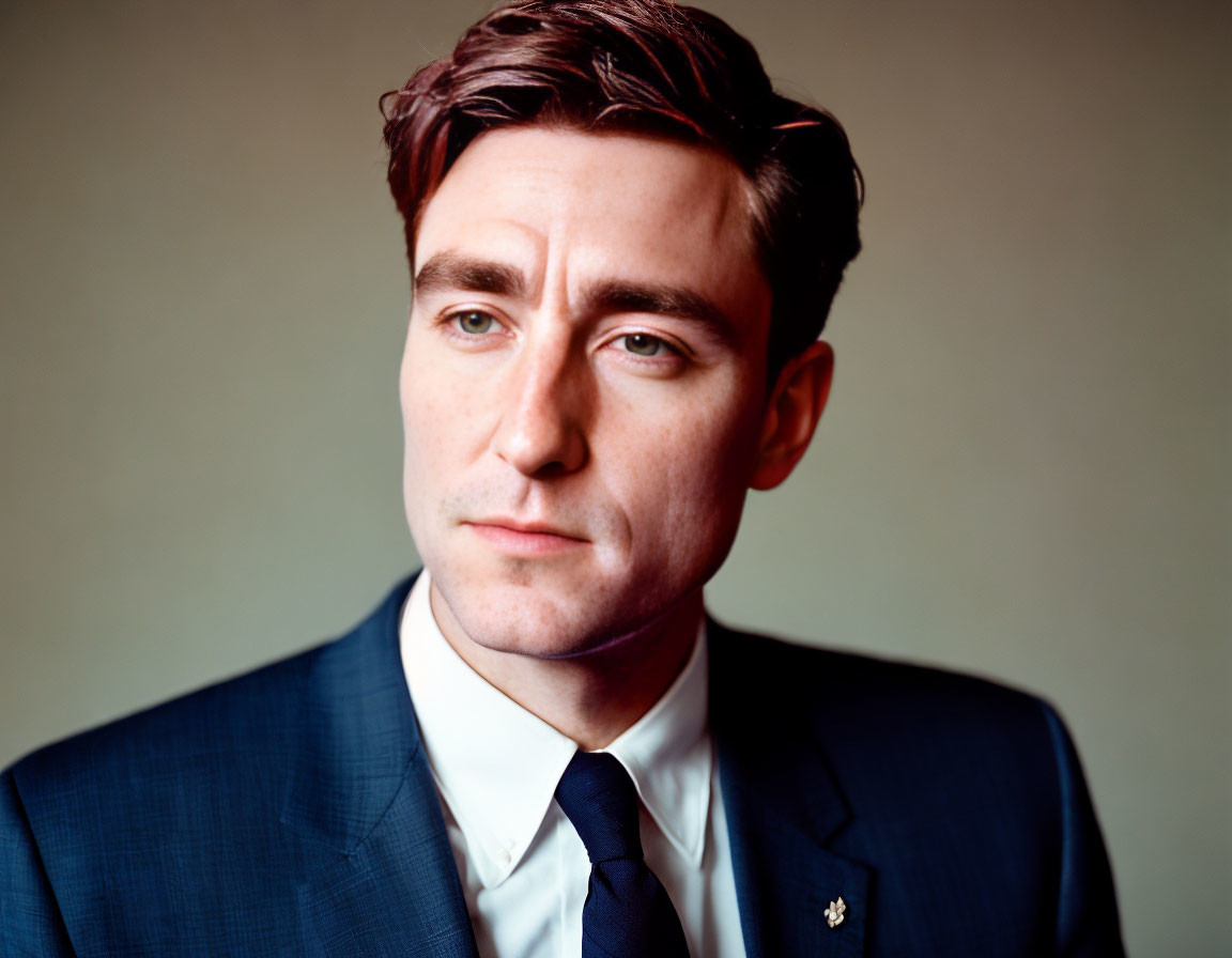 Man in Blue Suit and Tie with Dark Hair in Contemplative Pose