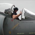 Multiple-engine aircraft with propellers flying through clouds with person in cockpit.