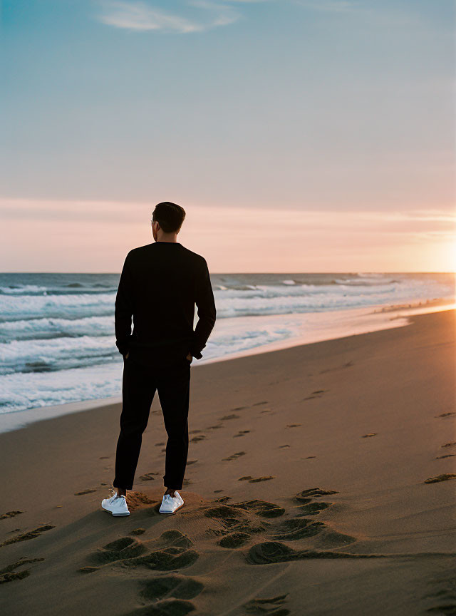 Person on Sandy Beach at Sunset with Footsteps in Sand