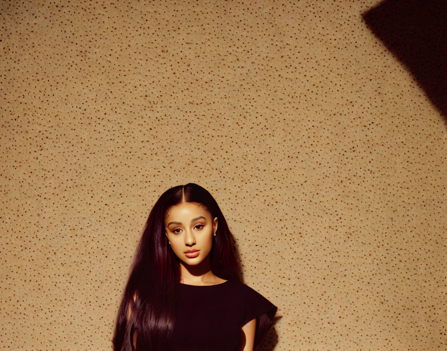 Woman with High Ponytail in Black Outfit Against Textured Beige Wall