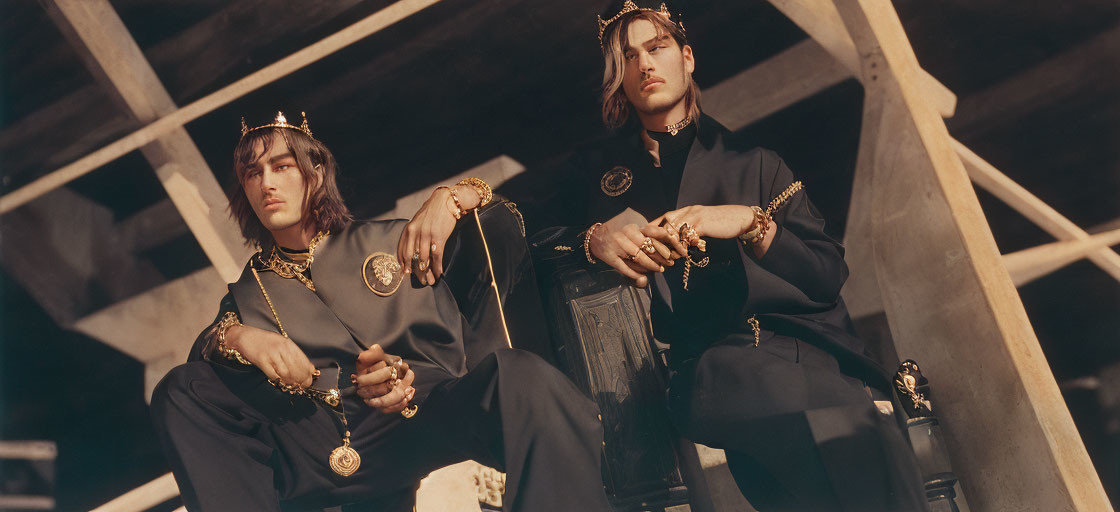 Luxurious Black and Gold Outfits with Crowns on Seated Individuals