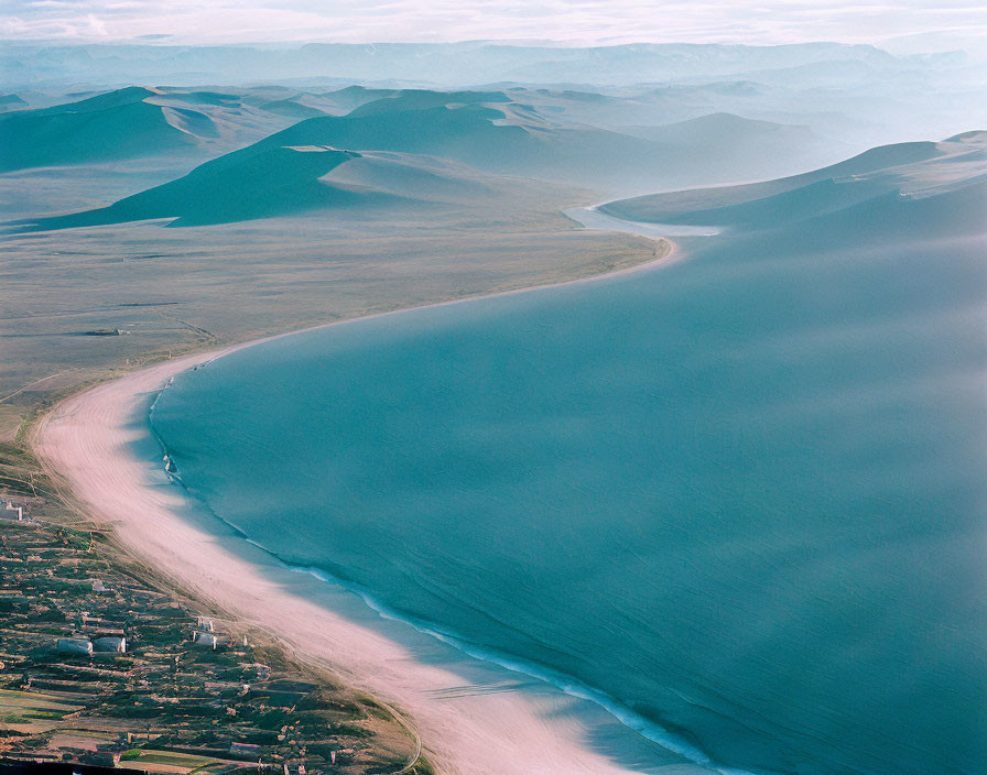 Curved Shoreline with Blue Water and Hilly Terrain in Aerial View