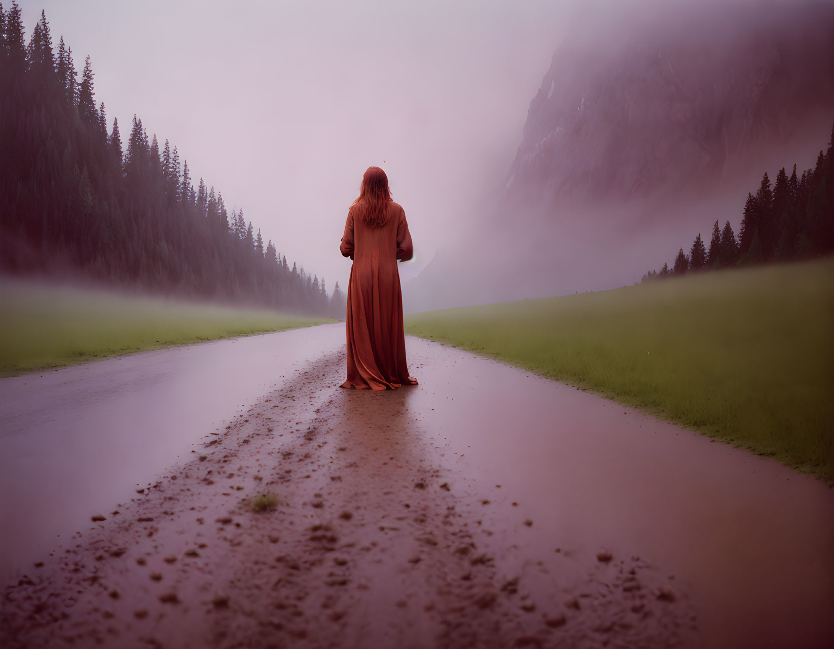 Person in Long Dress Standing on Wet Road in Foggy Forest Landscape