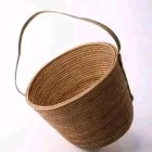 Woven wicker basket with curved handle on light pink background