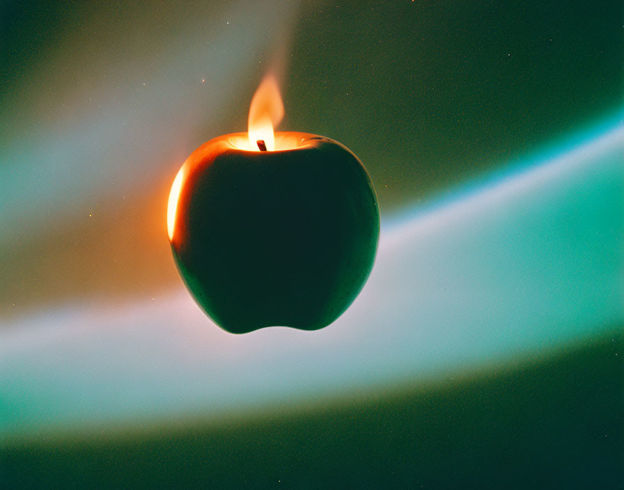 Apple-shaped candle illuminated against vibrant green and blue aurora backdrop.