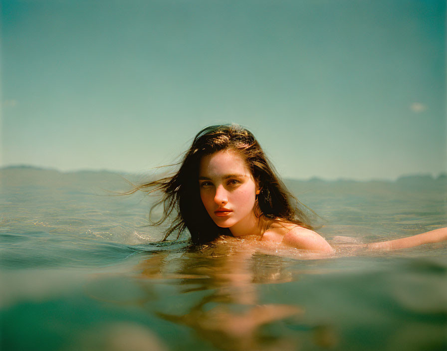 Long-haired woman half-submerged in water with soft-focused background