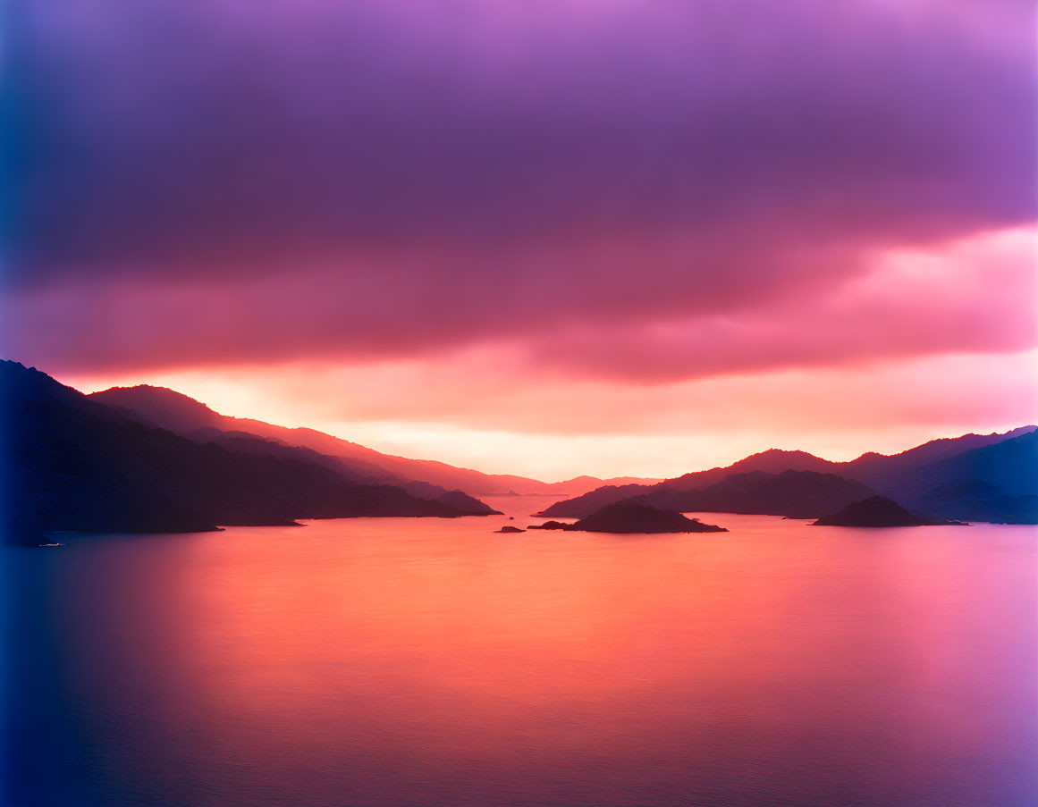 Tranquil Sunset Scene: Purple and Orange Skies Reflecting on Lake with Mountain Silhouette