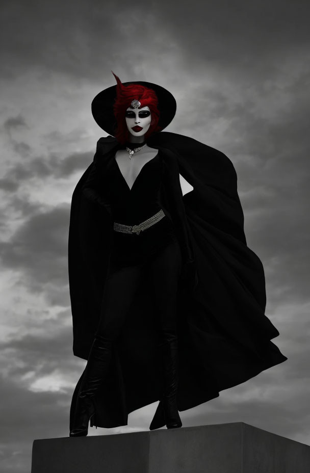 Person in dramatic black costume with wide-brimmed hat and red accents against cloudy sky