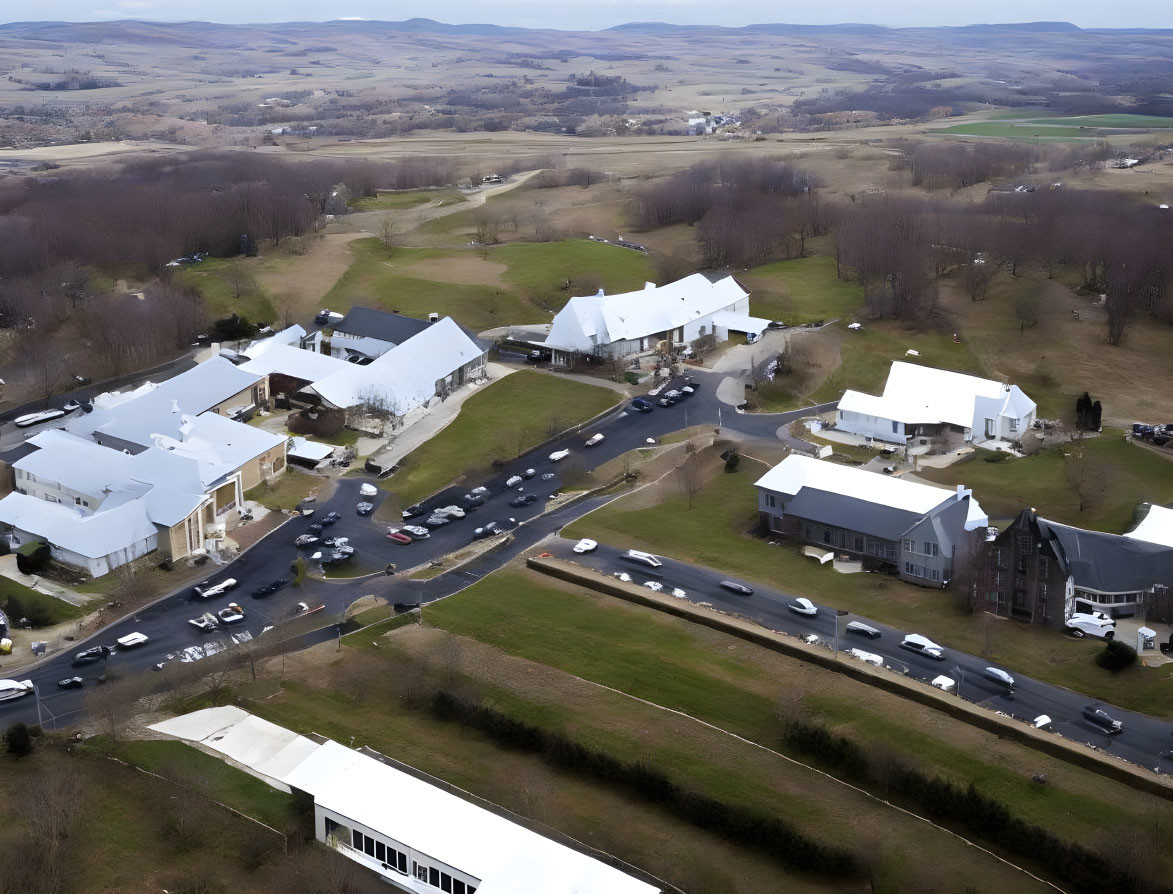 Complex with Multiple Buildings, Parking Spaces, and Green Fields from Aerial View