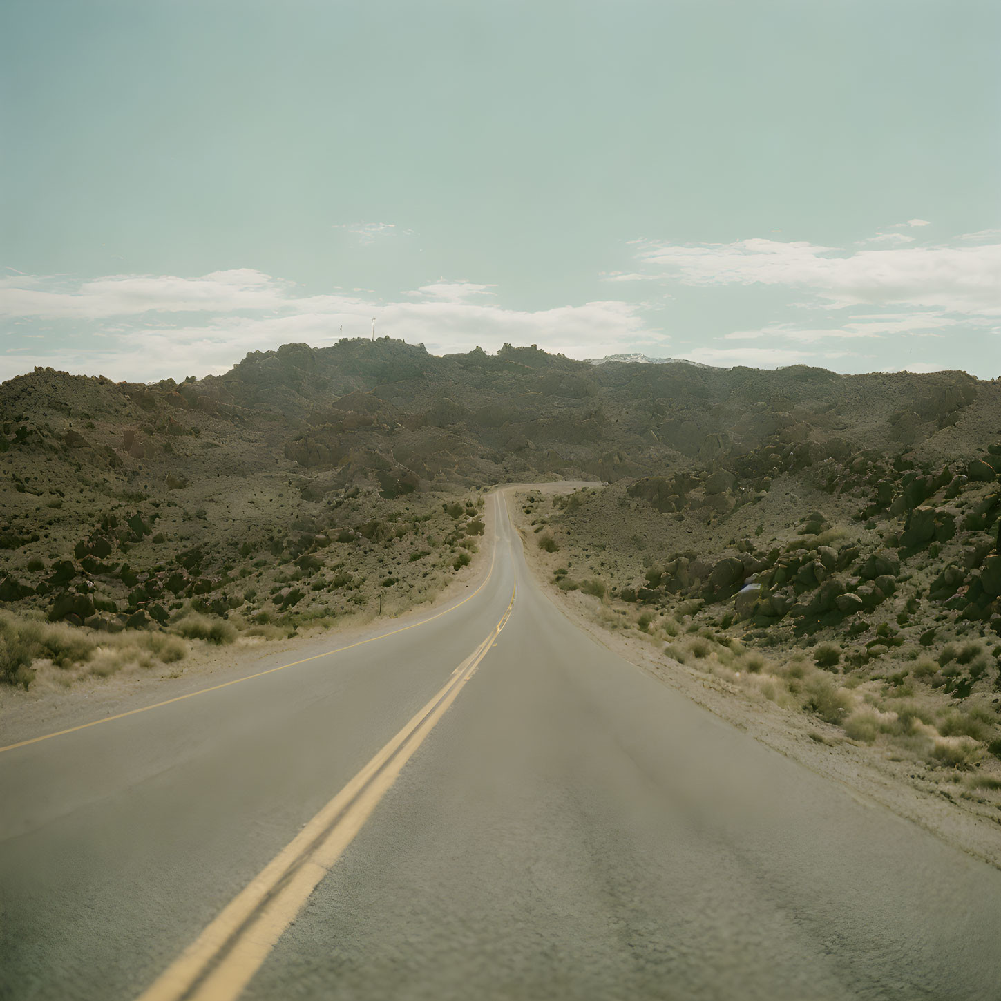 Desolate desert landscape with long straight asphalt road