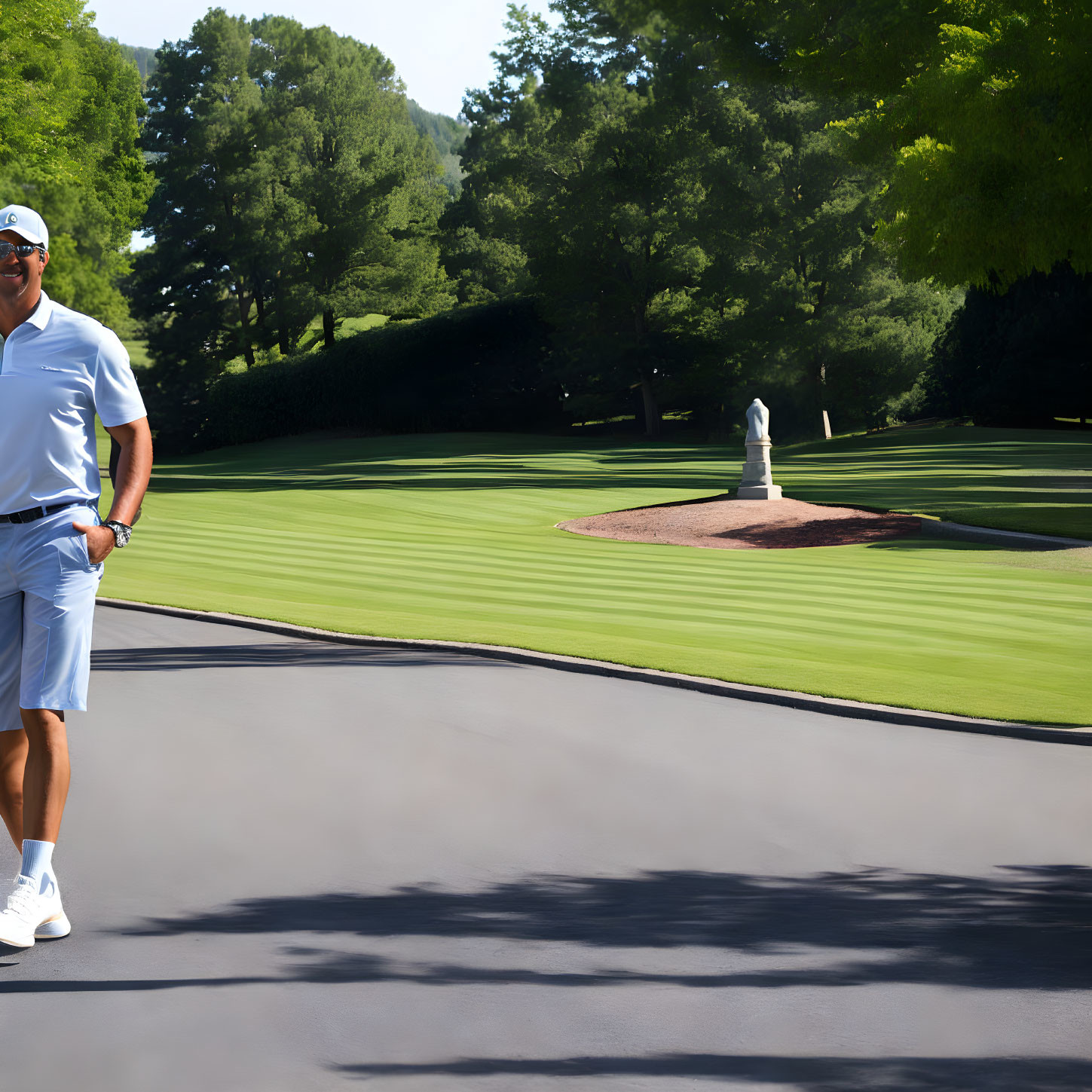 Person in white cap, sunglasses, t-shirt, shorts, and sneakers walking on paved path with trees