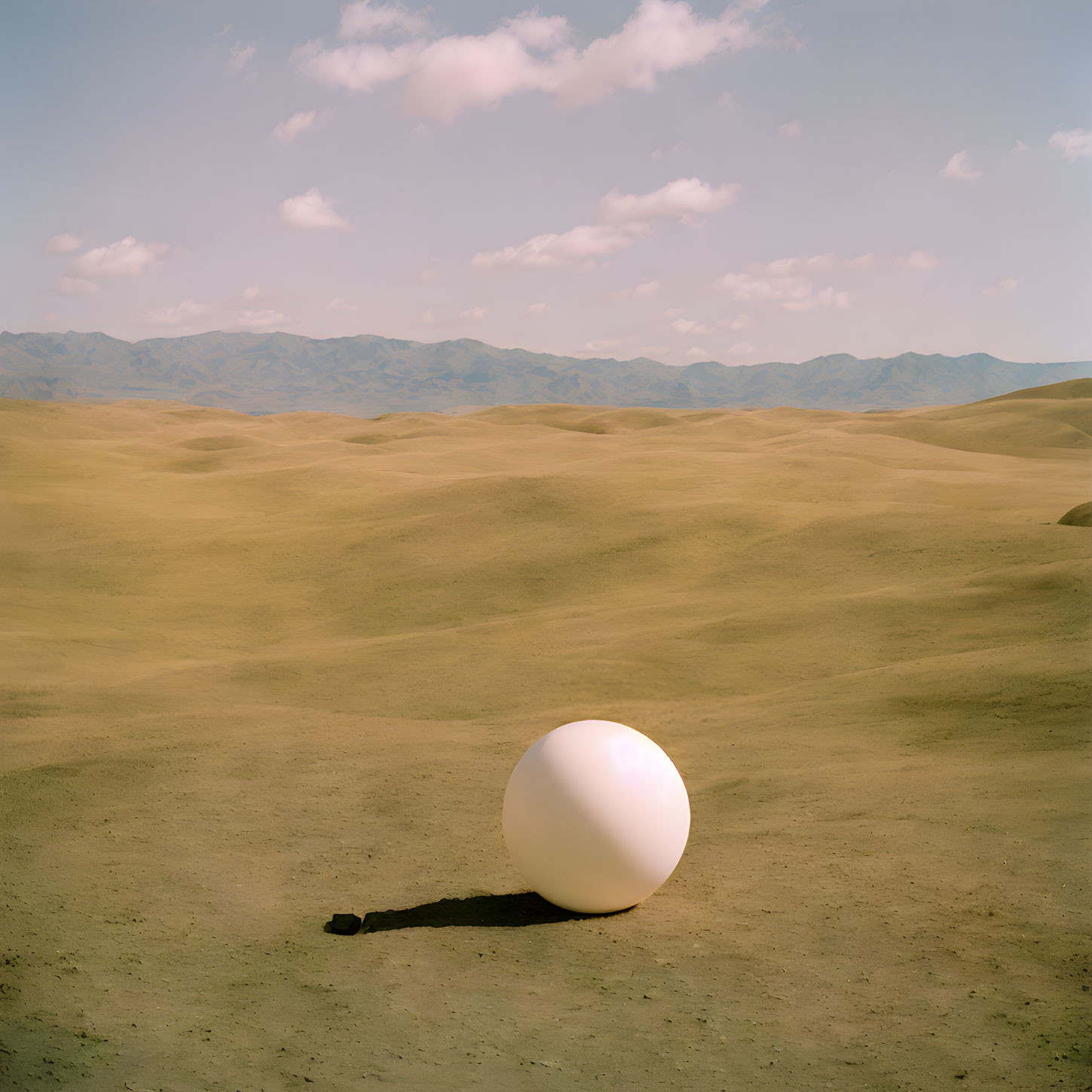 White Sphere in Barren Desert Landscape with Blue Sky