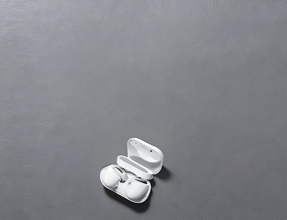 White Wireless Earbuds and Charging Case on Grey Background