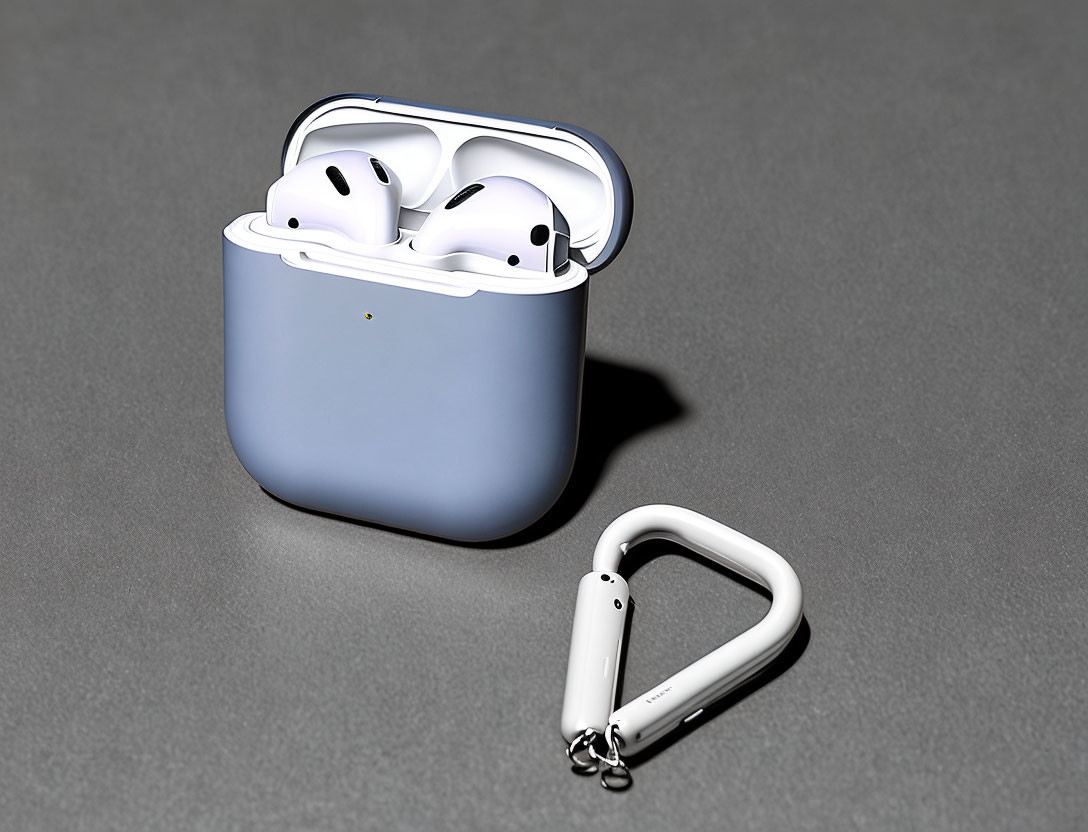 White Wireless Earbuds with Blue Case and Single Earbud on Gray Surface