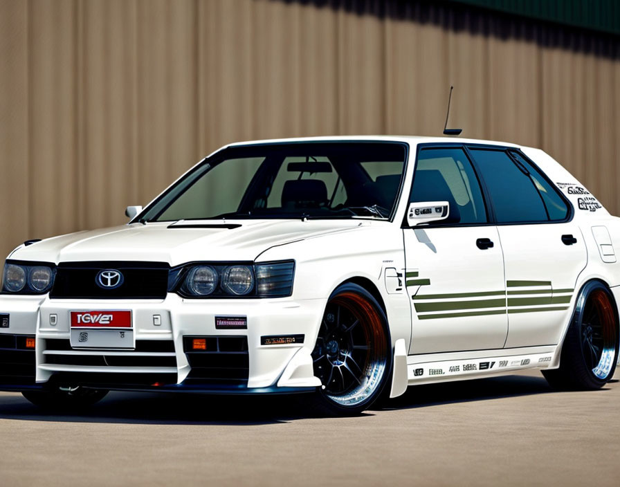 Customized white Toyota station wagon with racing decals and aftermarket wheels parked.