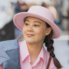 Smiling woman in pink hat and coat with pastel roses and succulents.