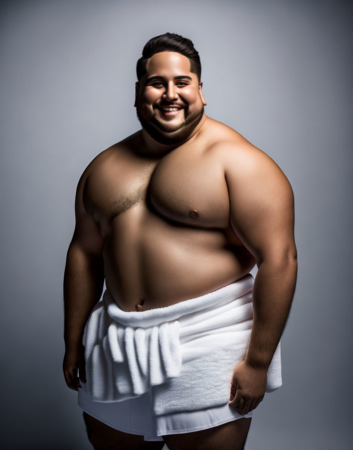 Robust man in white towel on gray background