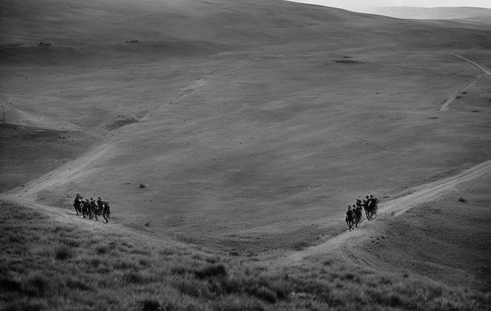 Horseback riders crossing vast hilly grassland