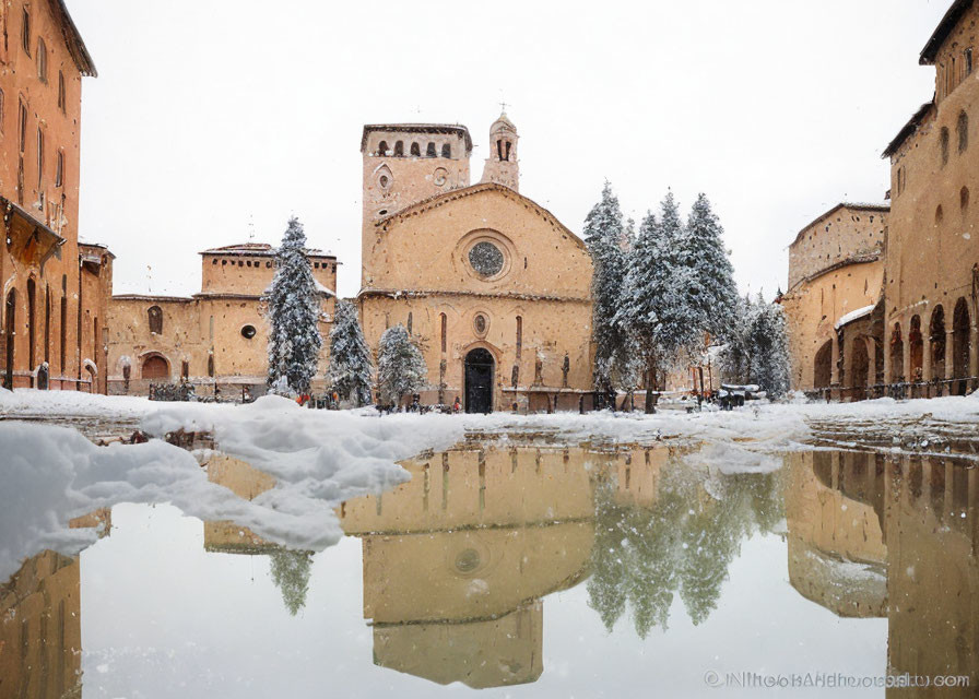 Snow-covered square with cathedral reflection and cloudy sky.