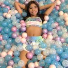 Colorful Balls and Bubbles Surrounding Cheerful Young Girl