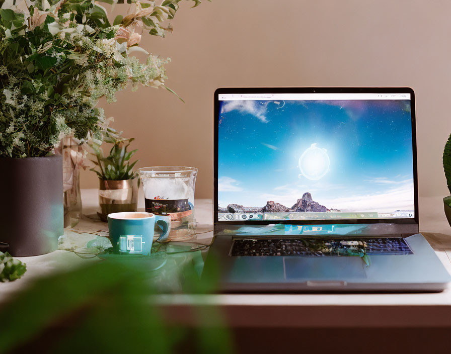 Laptop with cosmic wallpaper, green plants, coffee cup, and water glass