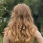 Blonde person with floral crown and butterflies in wavy hair