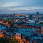 Fantasy city at dusk with illuminated windows and misty mountain backdrop