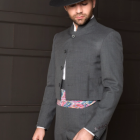 Vintage man in grey suit, vest, white shirt, black hat against dark background