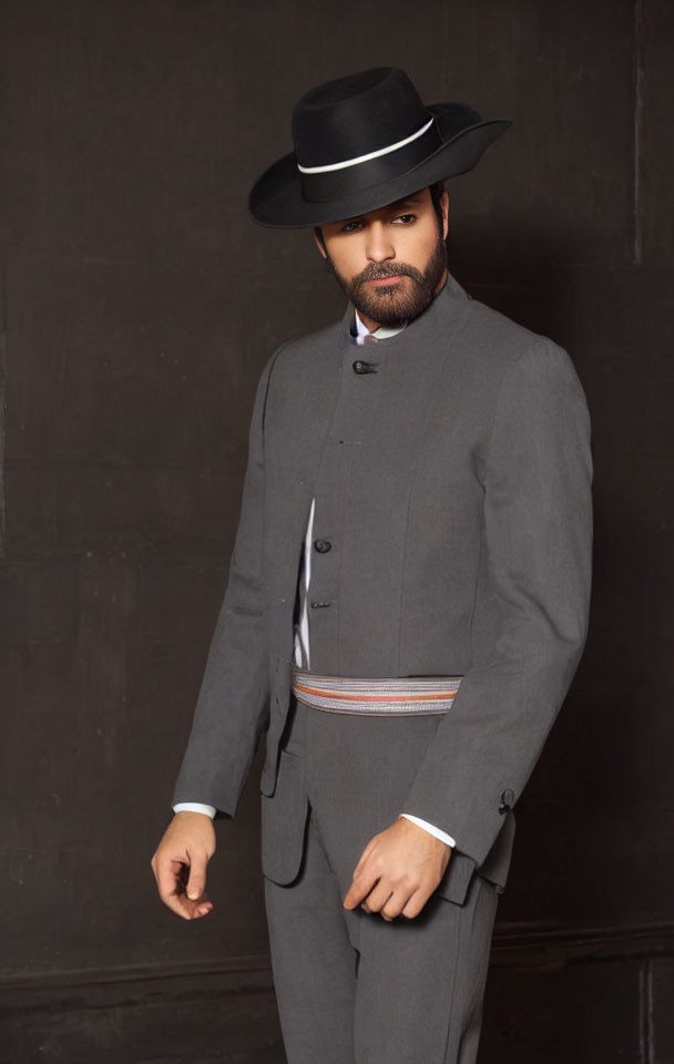 Vintage man in grey suit, vest, white shirt, black hat against dark background