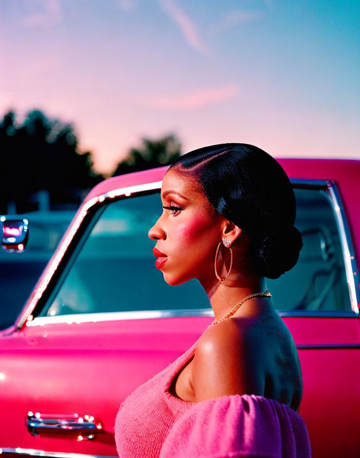 Woman in Pink Top Poses by Classic Pink Car at Sunset