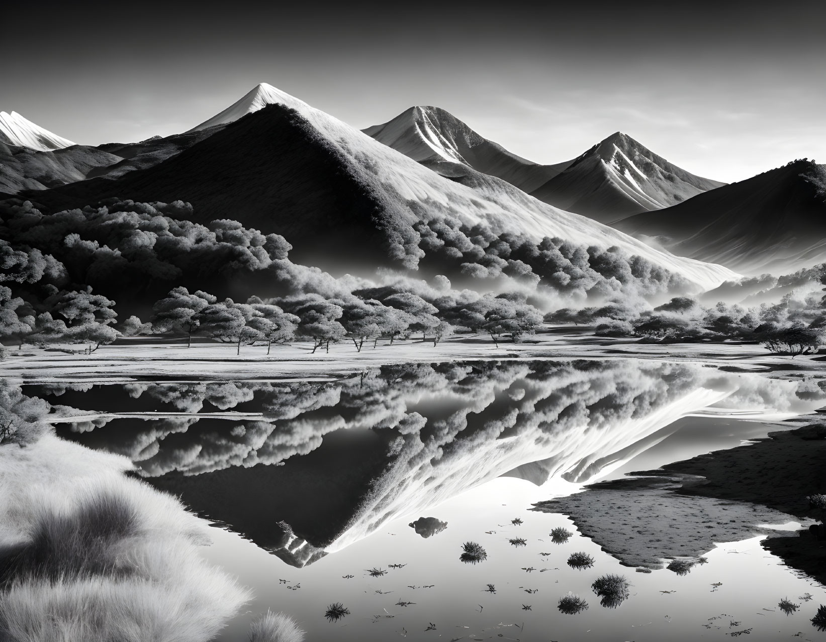 Snow-capped mountains reflected in tranquil lake amidst serene monochrome landscape