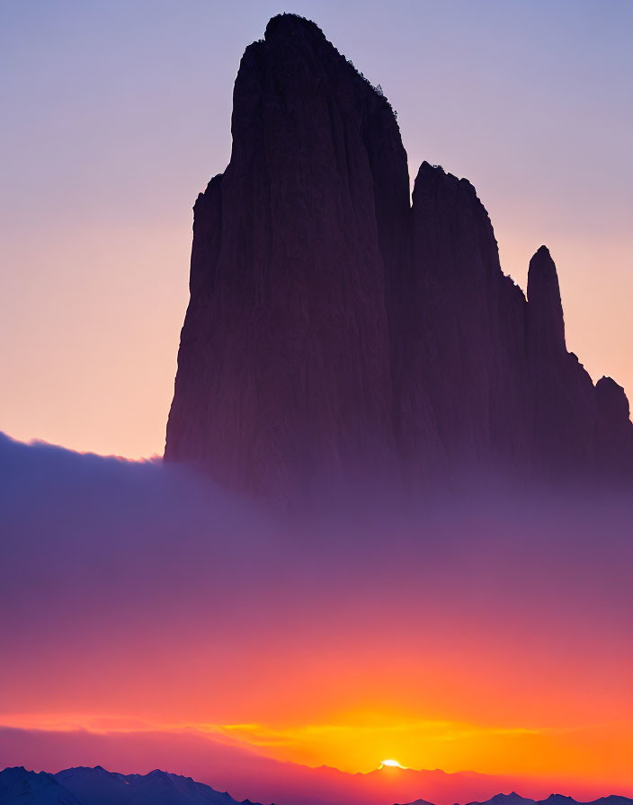 Mountain Peak Silhouette Against Vibrant Sunset Sky with Purple to Orange Gradient Clouds