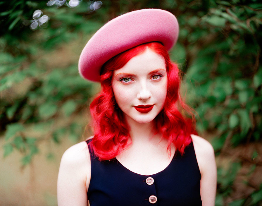 Red-haired woman in pink beret and black dress against green foliage