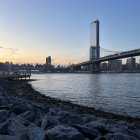 Cityscape painting: Decorative bridge over river, cloudy sky, birds, light, rocky shoreline