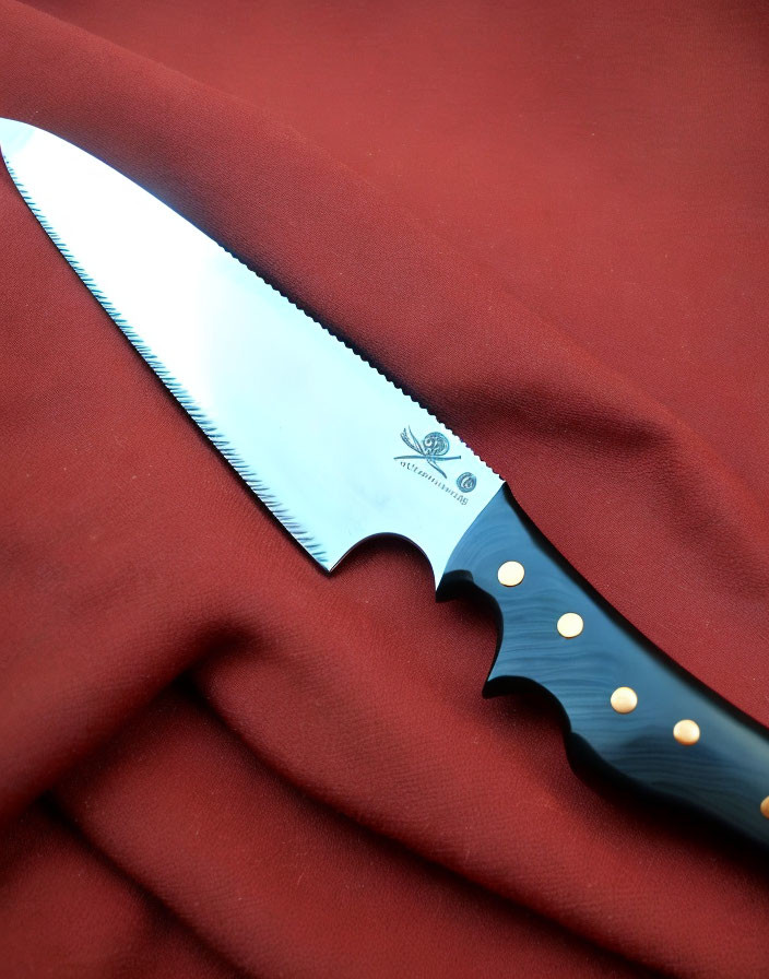 Serrated bread knife with black handle on crumpled red fabric