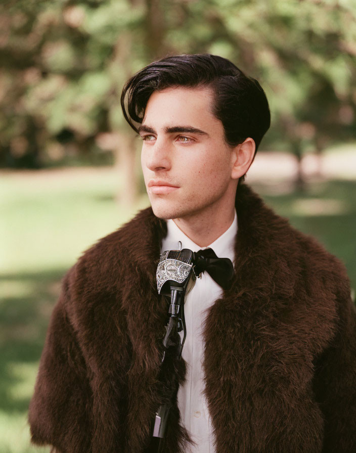 Man with Dark Hair in Bow Tie and Fur Stole at Outdoor Microphone