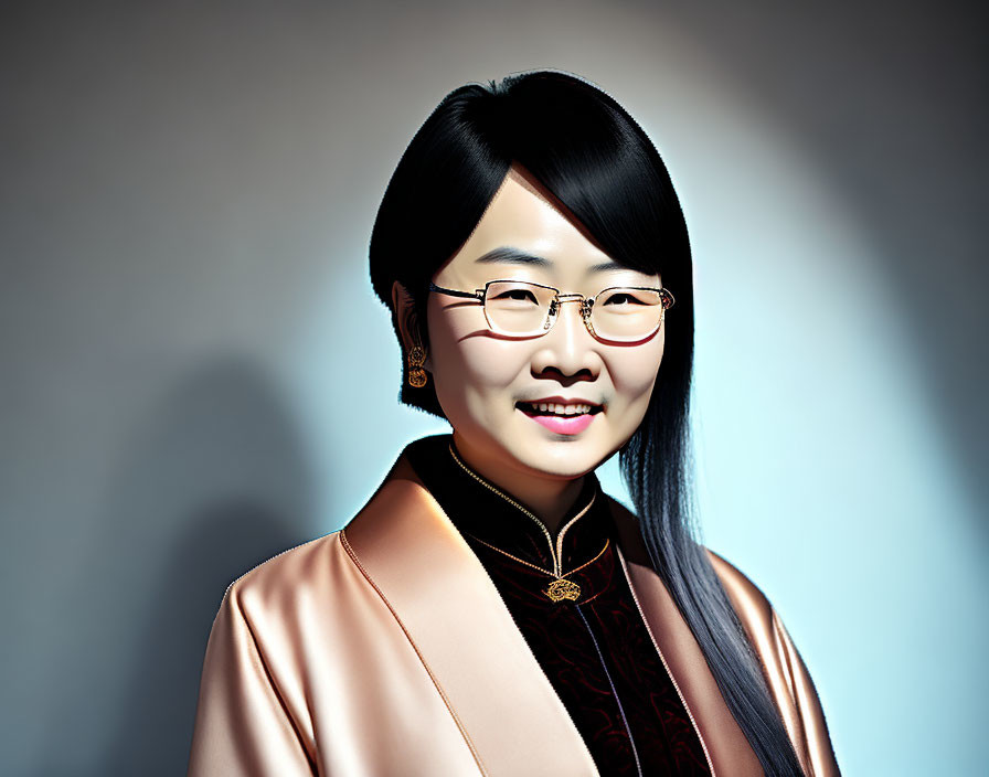 Smiling woman with black hair and glasses in pink blouse on grey background