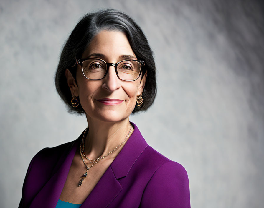 Gray-haired woman in purple blazer and accessories on gray background