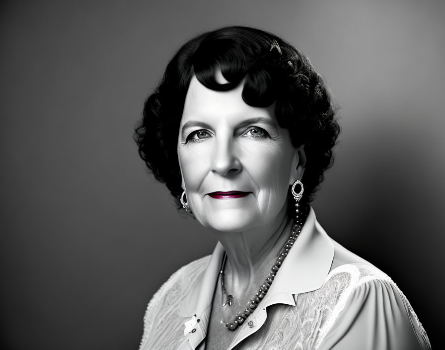 Elderly woman portrait with confident smile, pearl jewelry, lace blouse in black and white.