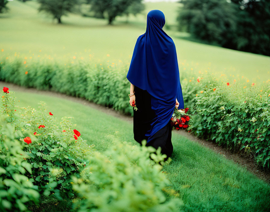 Woman in Blue Hijab Walking Along Garden Path with Bouquet