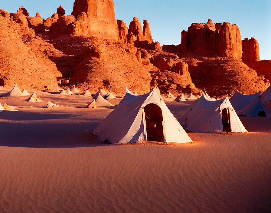 White Tents in Desert with Reddish Sand and Rock Formations