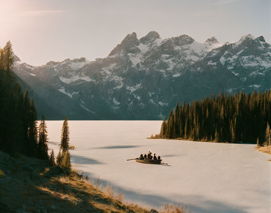 Golden sunset over serene lake with rowing boat and snow-capped mountains