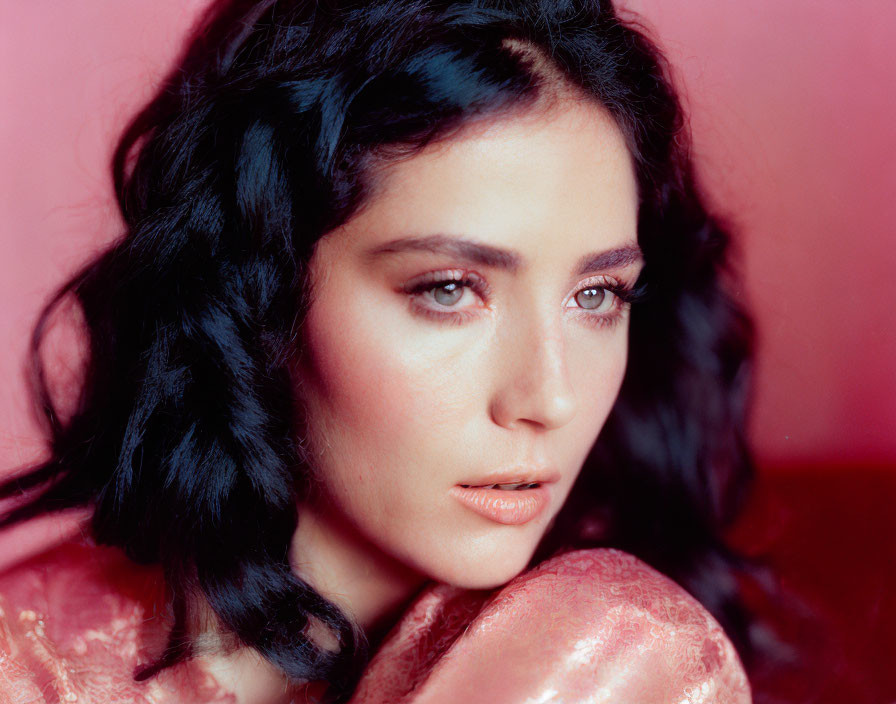 Dark Wavy-Haired Woman in Rose Outfit on Pink Background